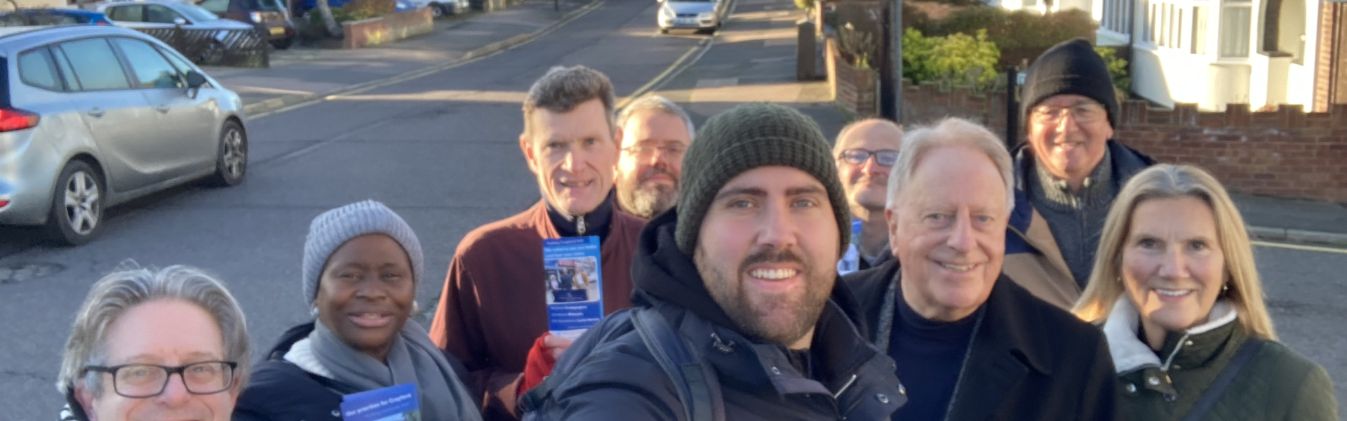A group photo of political campaigners facing the camera, smiling holding conservative party leaflets