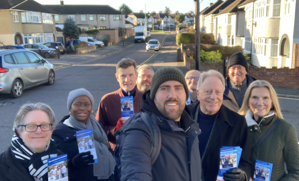 A group photo of political campaigners facing the camera, smiling holding conservative party leaflets